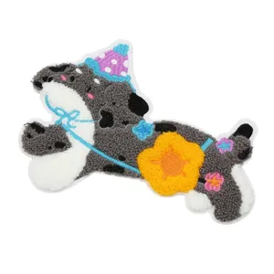Close-up detail of cute cartoon puppy towel embroidery patch with party hat and flower.