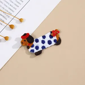 Detail shot of a cute cartoon puppy embroidery patch, featuring blue polka dots.