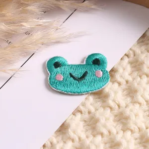 Close-up detail of a cute green frog embroidered patch, perfect for DIY clothing accessories decoration.
