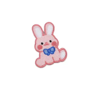 Cute pink rabbit embroidered patch with blue bow, ideal for clothing DIY and apparel decoration.