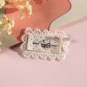 Close up of cute Korean style lace fabric patch with embroidery tag and bow detail.