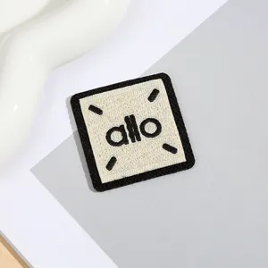 Detailaufnahme eines minimalistischen quadratischen bestickten Patches mit allo Text.