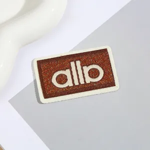 Nahaufnahme eines braunen bestickten Buchstaben-Patches mit weißem Rand für Textilien.