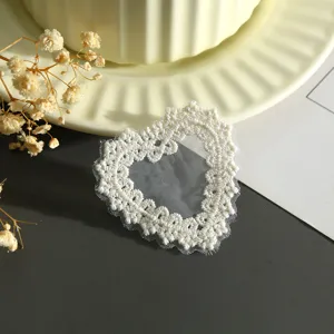 Dettaglio di patch in pizzo bianco a forma di cuore, accessorio fai da te per vestiti.