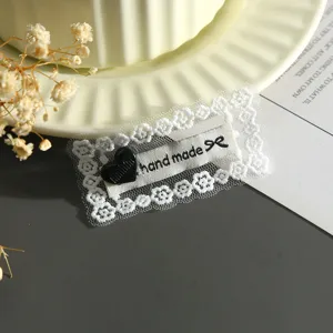 Close-up detail shot of lace embroidered heart patch with hand made woven label and ribbon.