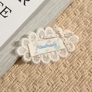 Nahaufnahme der weißen Spitzenstickerei Applikation mit Handmade Etikett für DIY Handwerk.