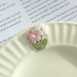 Cute 3D embroidered flower patch with pink and white petals and green leaves for DIY clothing.