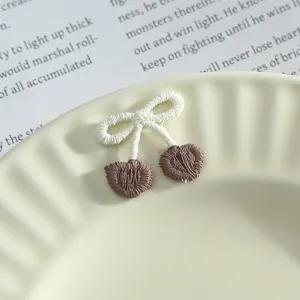 Close-up detail of cute embroidered bow and cherry patch, fine textile texture for DIY decor.