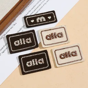 Nahaufnahme bestickter Buchstaben-Stoffpatches mit Herzen für Kleidung und DIY-Projekte.