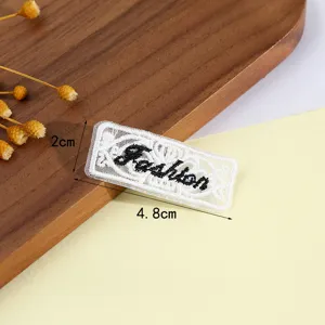 Vista detallada del parche de letras bordadas huecas, delicada textura de encaje para bricolaje.