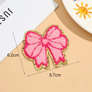 Pink bow towel embroidery patch with gold glitter edge for DIY clothing accessories and crafts.