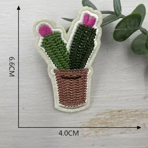 Detailed view of cute cactus embroidered patch with pot and pink flower for clothing decor.