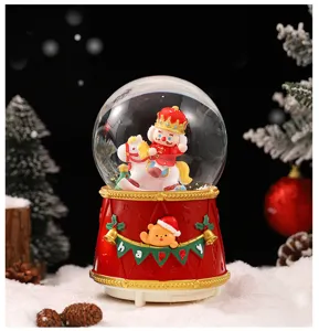 Detailed view of Christmas snow globe with cute king and festive bear base, resin decor.