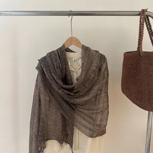 Detail view of the brown crinkled scarf with golden threads and fringe for women.