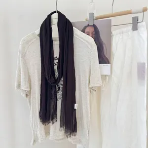 Detail view of a solid color pleated skinny scarf, featuring a lightweight and retro texture.