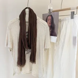 Close up view of a stylish brown pleated long scarf draped on a casual t shirt display.
