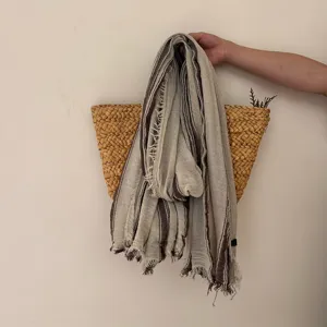 Close-up detail showing the rustic striped pattern and frayed raw edges of the linen cotton scarf.