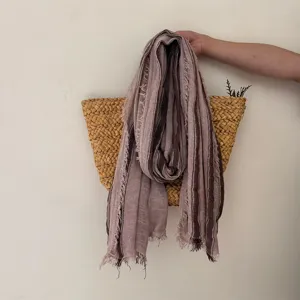 Close-up detail of the rustic striped cotton-linen scarf with raw fringe edges, texture view.