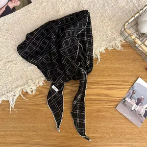Detailed view of retro black and white checkered triangular scarf with scalloped white edges.