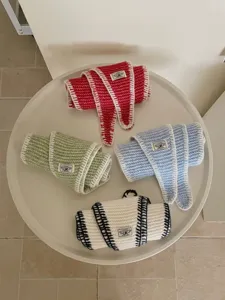 Detailed view of colorful knitted diamond scarves rolled neatly with custom labels.