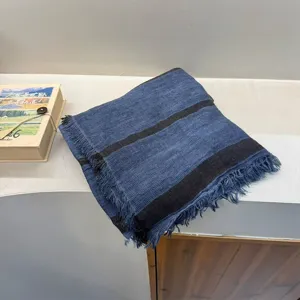 Retro striped linen scarf detail showcasing blue and black pattern with stylish fringe edges.