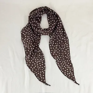 Detailed view of the brown polka dot silk scarf, showing the fine fabric and diagonal tip.