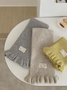 Detailed shot of soft knitted winter scarves with cute ruffled ends in multiple chic colors.