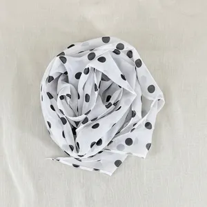 Detailed close-up shot of the elegant black and white polka dot silk scarf texture and fine fabric.