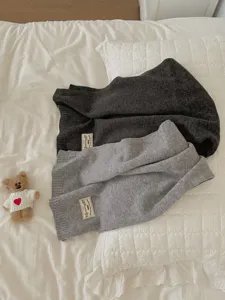 Cozy knit scarf detail showcasing soft wool material, elegant woven label and neutral grey colors.