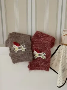 Charming knit scarf detail featuring cute embroidered horse patch, cozy winter fashion accessory.