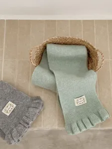 Cozy knitted winter scarf with delicate ruffled edge detail, soft wool blend material, stylish item.