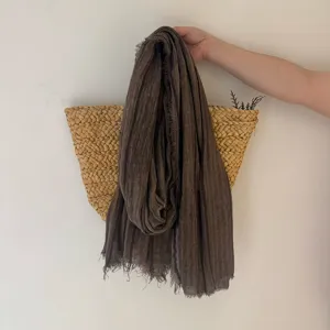 Gros plan d'écharpe marron foncé avec texture fine, détails de franges effilochées et style rétro.