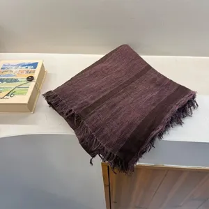 Detailed view of a dark purple striped cotton-linen scarf with fringed edges, elegantly folded.