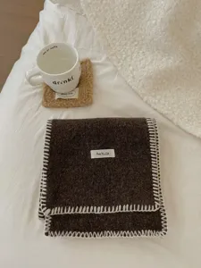 Bufanda de punto gruesa con borde overlock blanco y diseño marron para el invierno.