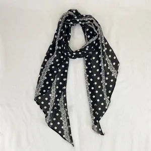 Close-up detail of the black and white polka dot scarf, showing delicate fabric texture.