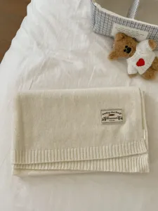 Cozy off-white knitted winter scarf with a stylish label. Soft and warm accessory for cold days.