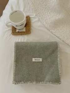 Primer plano de bufanda de punto de color sólido con puntada blanca y etiqueta.
