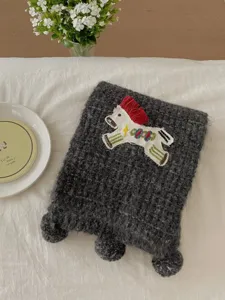 Detail shot of the knitted pony scarf, cozy winter neckerchief with cute embroidered horse.