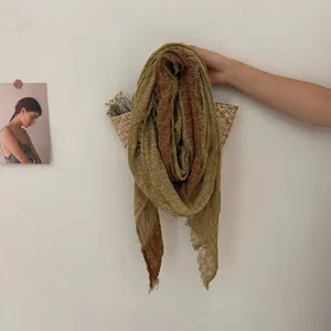 Vue détaillée d'une écharpe patchwork vintage usée, suspendue dans un panier en osier texturé.