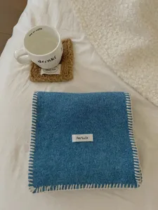 Primer plano detallado de bufanda de punto azul acogedora con costura blanca y etiqueta.