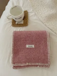 Vista detallada de una bufanda de punto de invierno rosa acogedora con borde blanco y etiqueta.