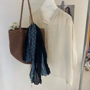 Vista dettagliata di camicia casual in lino a maniche lunghe con borsa intrecciata e sciarpa.