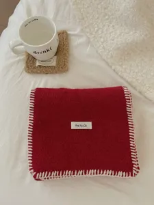 Detalle de bufanda de punto rojo acogedor con bordes de puntada de manta y etiqueta elegante.
