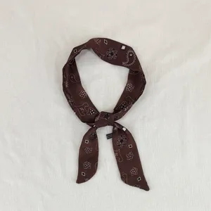 Primo piano di un foulard sottile vintage marrone scuro con elegante stampa paisley floreale.
