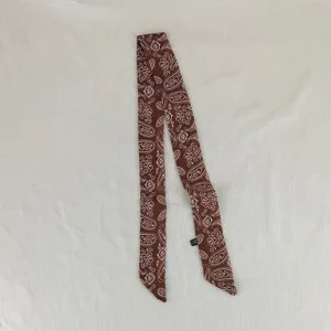 Dettaglio foulard twilly con stampa paisley marrone, piccolo nastro retrò per collo e capelli.