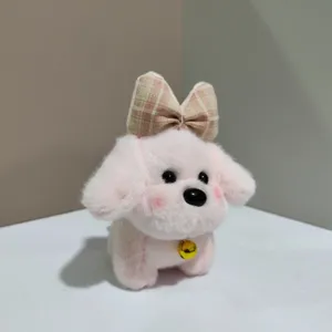 Cute pink puppy plush toy detail view, fluffy doll with plaid bow and bell pendant.