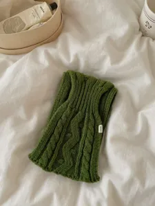 Détail d'écharpe en tricot torsadé vert uni rétro, accessoire texturé doux pour style cosy.
