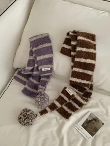 Cozy striped knitted scarf detail with fluffy pom-poms, soft winter fuzzy neck warmer.
