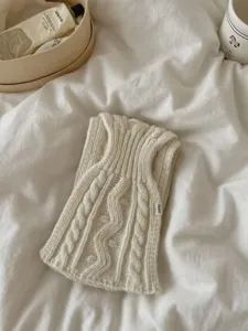 Détail d'écharpe en maille torsadée douce crème, accessoire de mode rétro automne, gros plan.