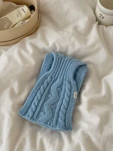 Vue détaillée d'une écharpe douillette en maille torsadée bleu clair, douce et élégante.